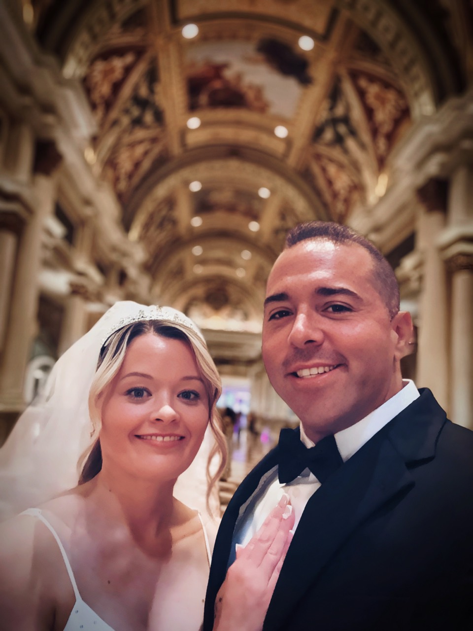 Jordan and Danielle in wedding attire inside an ornate grand hall
